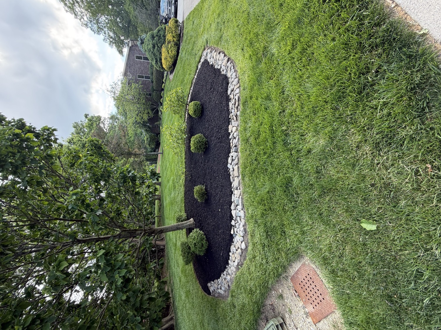 Garden bed with stone border, mulch, and ornamental plantings
